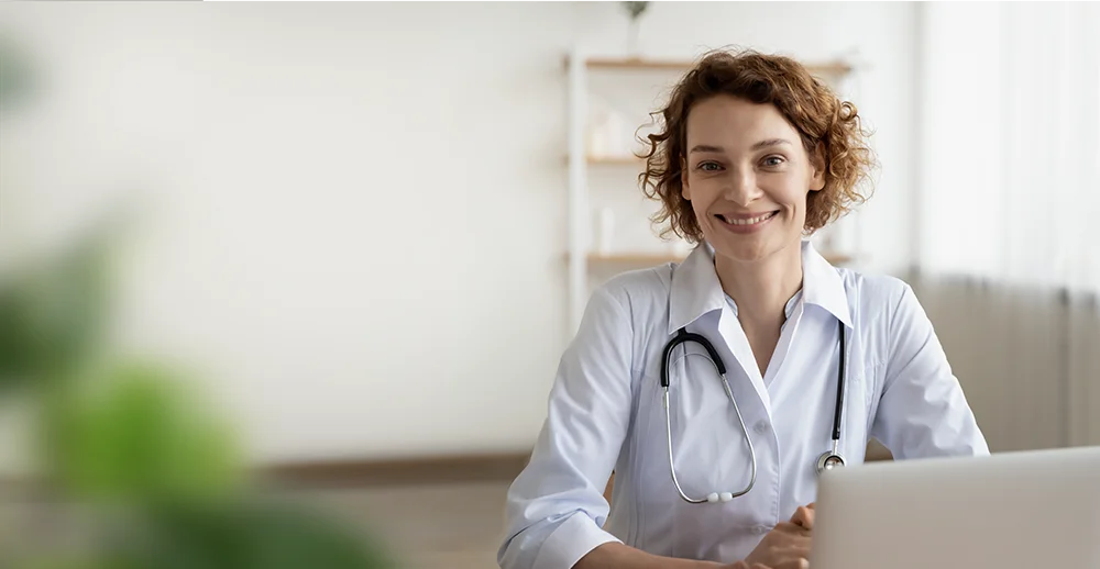 Ärztin schaut lächelnd in die Kamera für den CallOnce ChatGPT-Praxisbot